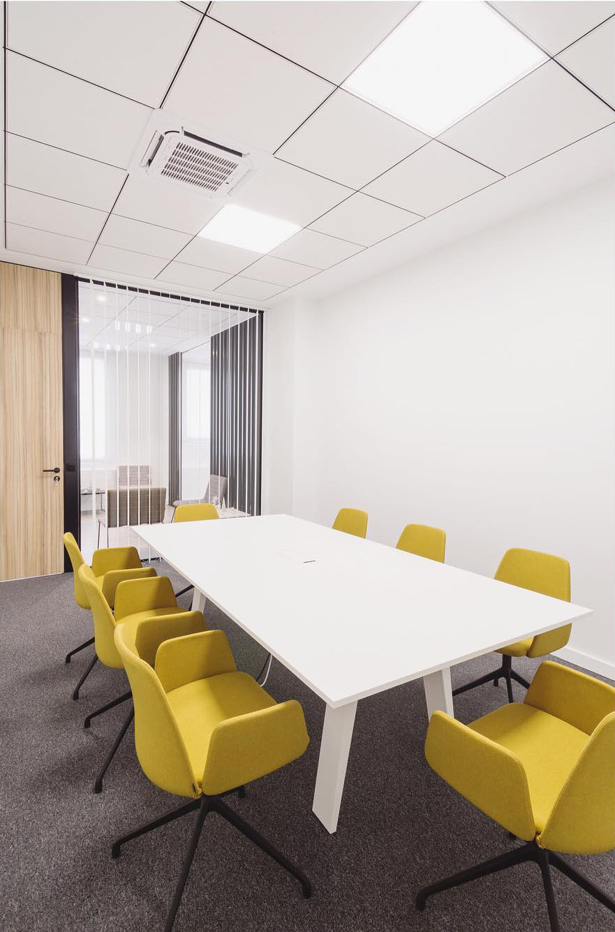 sala de reuniones con mesa blanca y sillas amarillas